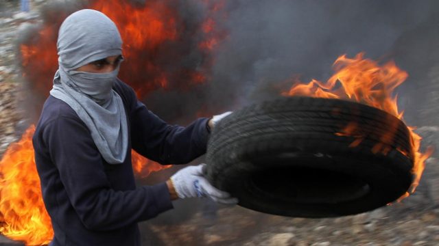 палестинец держит горящую шину