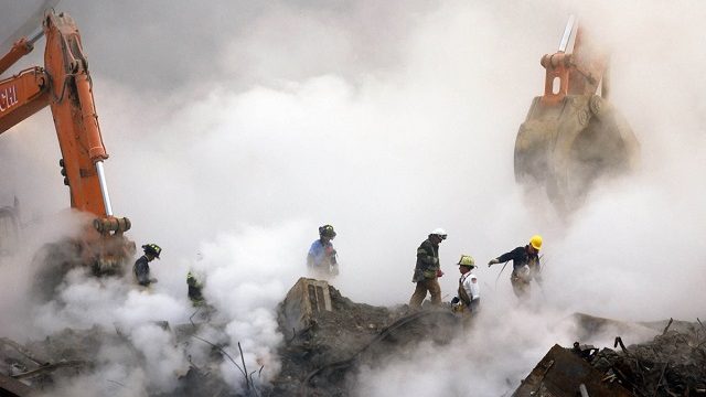 Спасатели пробираются сквозь руины торгового центра, охваченные облаком пыли и дыма. Нью Йорк, 11 сентября 2001 г.