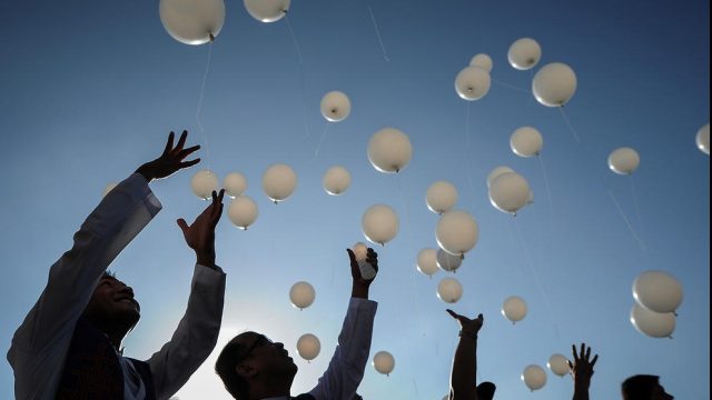 люди отпускают белые воздушные шары